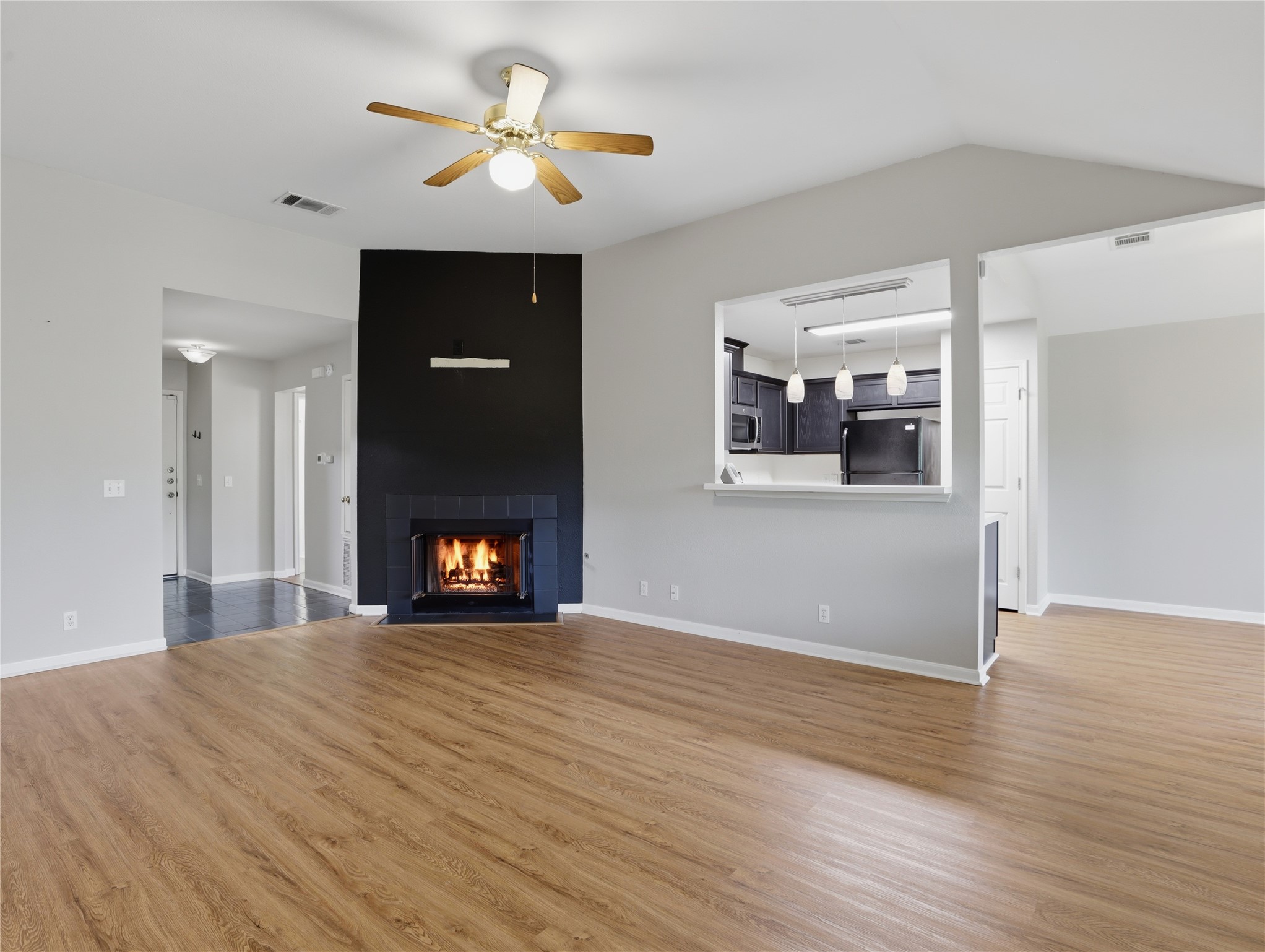 168 Keystone Loop Kyle, TX 78640 - Photo 6 of 23 Unfurnished living room with a ceiling fan, a large fireplace, wood finished floors, and vaulted ceiling