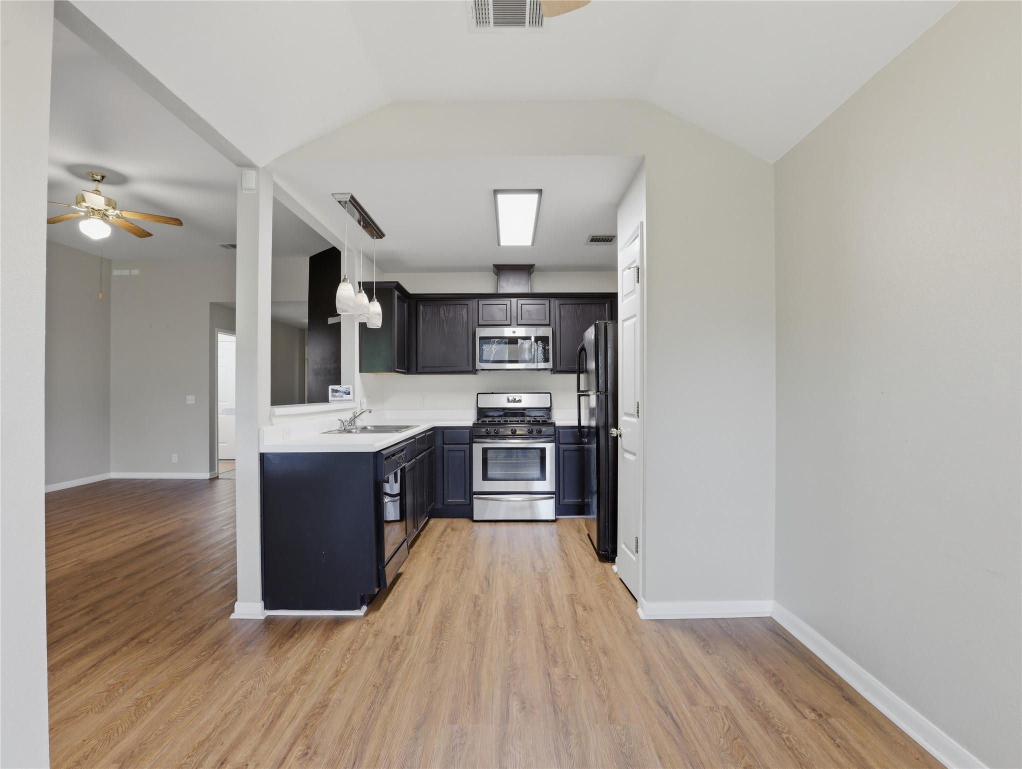 168 Keystone Loop Kyle, TX 78640 - Photo 7 of 23 Kitchen with light countertops, black appliances, a ceiling fan, light wood-type flooring, and pendant lighting
