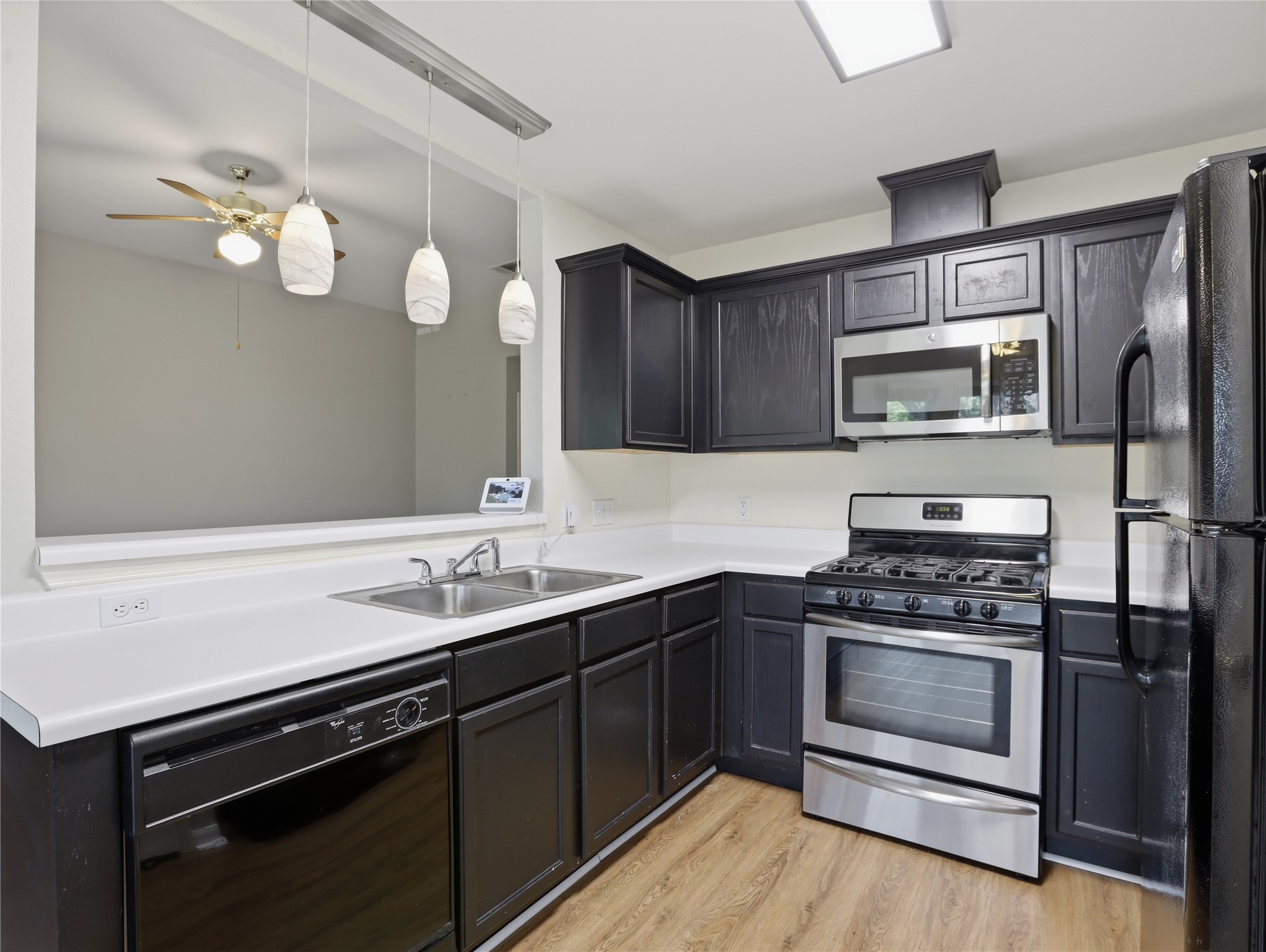 168 Keystone Loop Kyle, TX 78640 - Photo 8 of 23 Kitchen featuring black appliances, light countertops, light wood finished floors, decorative light fixtures, and a ceiling fan