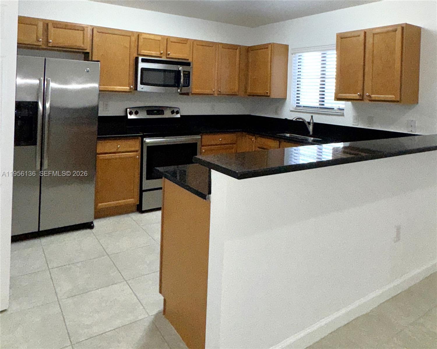 22441 Southwest 88th Place, Unit 2015 Cutler Bay, FL 33190 - Photo 8 of 19 a kitchen with stainless steel appliances granite countertop a refrigerator a stove and a sink with wooden cabinets
