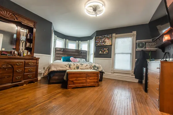 a bedroom with a bed next to a window with dresser
