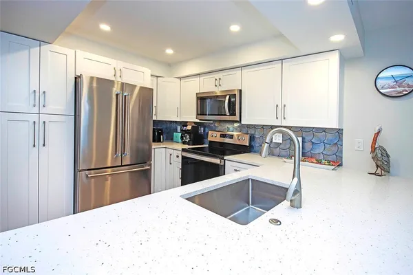 a kitchen with stainless steel appliances kitchen island granite countertop a refrigerator a stove a sink a oven with a dining table and chairs