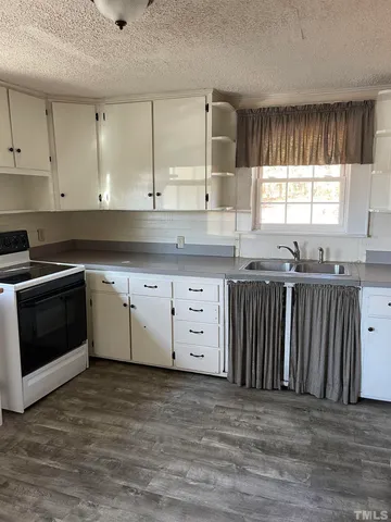a kitchen with granite countertop a stove a sink and a microwave