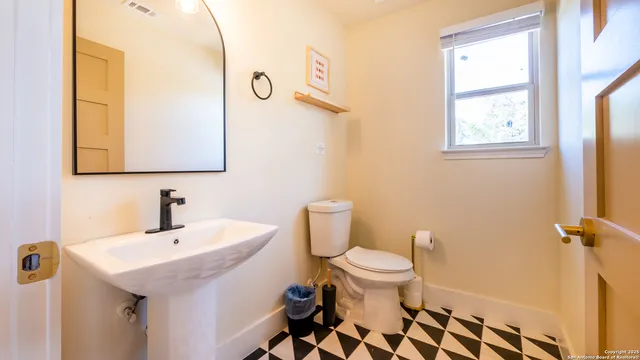 a bathroom with a sink a toilet a mirror and shower curtain