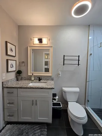 a bathroom with a granite countertop toilet sink and mirror