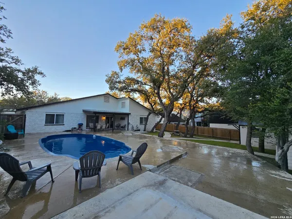 a view of house with outdoor seating and covered with trees