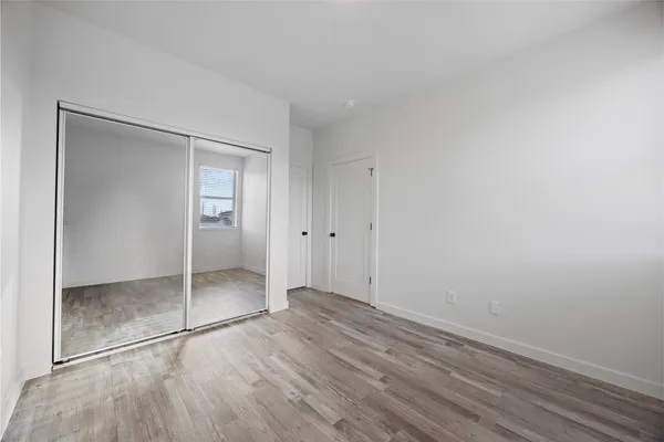 a view of an empty room with wooden floor and closet