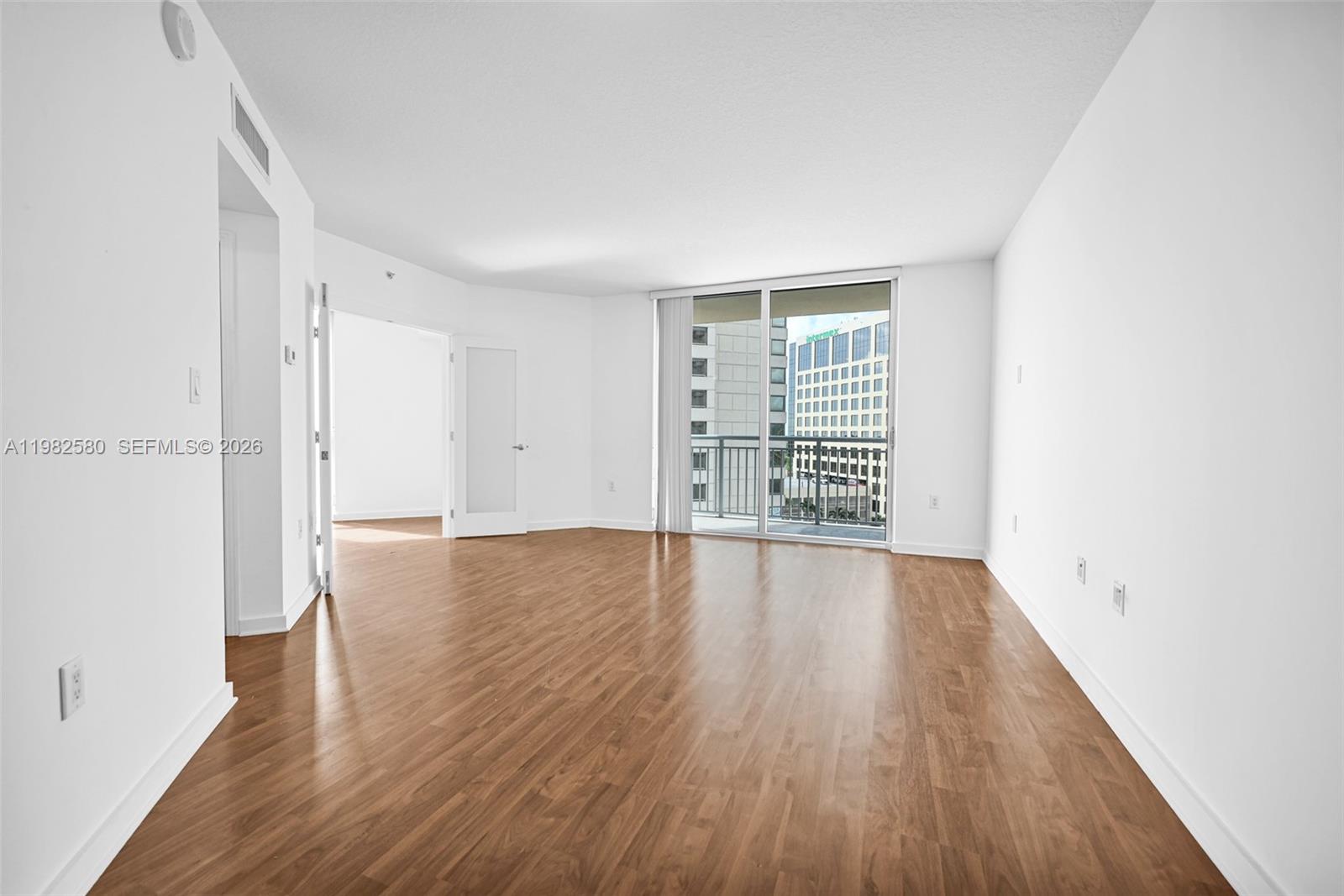 9055 Southwest 73rd Court, Unit 1104 Miami, FL 33156 - Photo 8 of 19 an empty room with wooden floor and windows