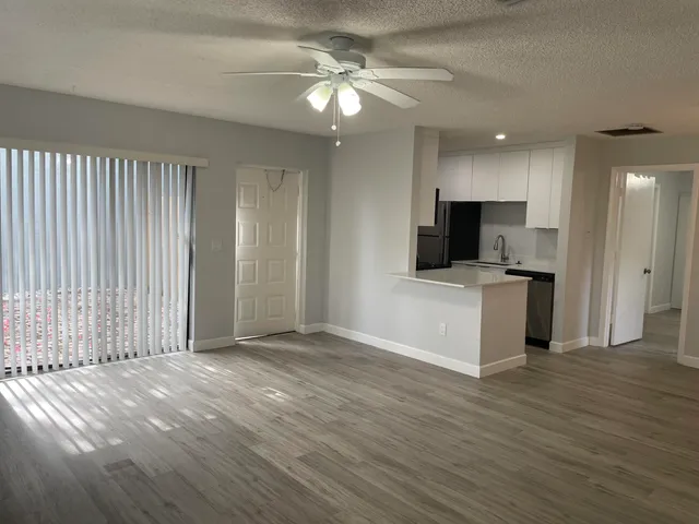a view of a kitchen with a sink cabinet a ceiling fan and a wooden floor