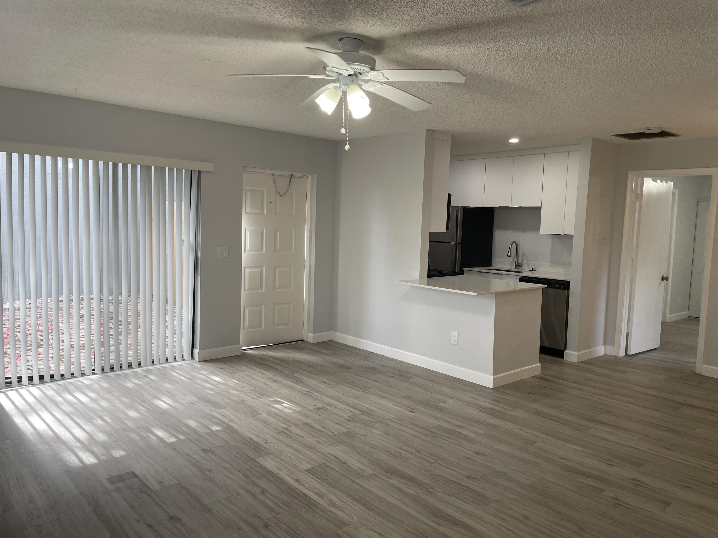 3 Crossings Circle, Unit A Boynton Beach, FL 33435 - Photo 5 of 21 a view of a kitchen with a sink cabinet a ceiling fan and a wooden floor