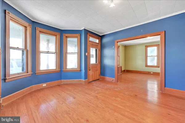 an empty room with wooden floor cabinet and windows
