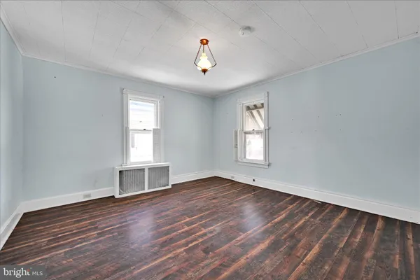 a view of an empty room with wooden floor and closet