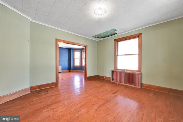 a view of an empty room with window and wooden floor