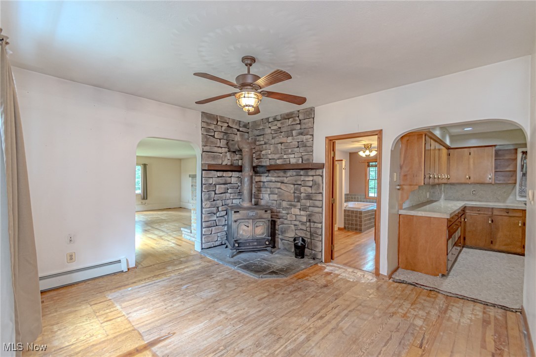 749 Hartman Road Wadsworth, OH 44281 - Photo 24 of 49 Unfurnished living room featuring light hardwood / wood-style flooring, ceiling fan, baseboard heating, and a wood stove
