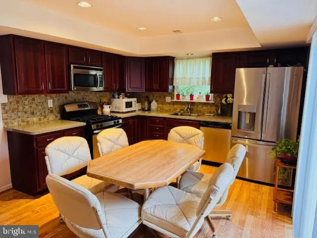 a kitchen with stainless steel appliances granite countertop a refrigerator a stove a sink dishwasher a dining table and chairs with wooden floor