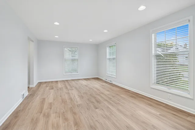 an empty room with wooden floor and windows