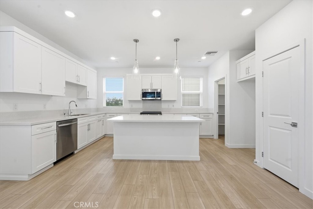 9335 Via Azul Pico Rivera, CA 90660 - Photo 11 of 55 a large white kitchen with a stove a sink dishwasher and a refrigerator with wooden floor