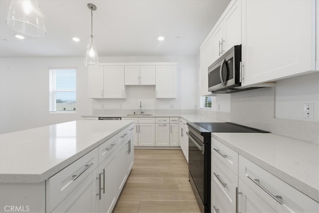 9335 Via Azul Pico Rivera, CA 90660 - Photo 17 of 55 a kitchen with stainless steel appliances granite countertop a sink and dishwasher a stove top oven with white cabinets