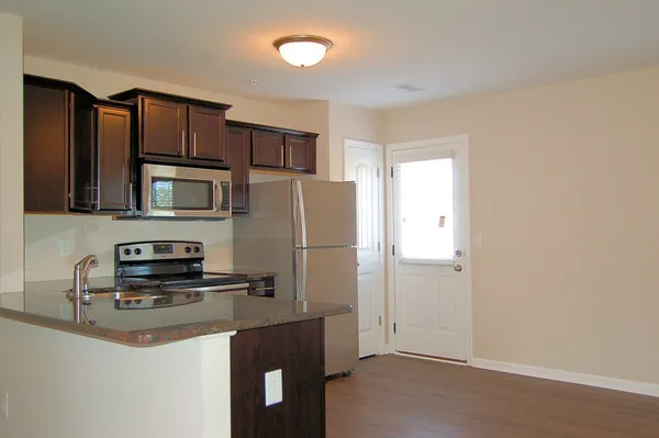 a kitchen with stainless steel appliances granite countertop a refrigerator a stove a sink and a microwave