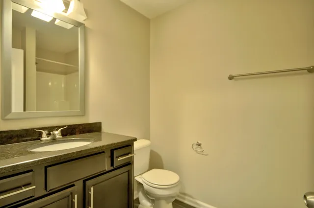 a bathroom with a granite countertop sink toilet and a mirror