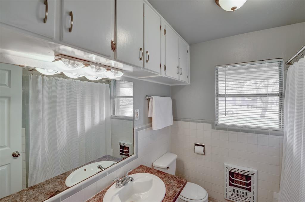 1002 North Stewart Street Azle, TX 76020 - Photo 6 of 29 a bathroom with a sink a toilet and shower curtain
