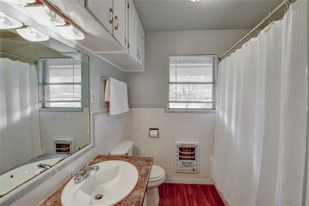 1002 North Stewart Street Azle, TX 76020 - Photo 8 of 29 a bathroom with a sink a toilet and shower curtain