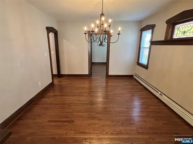 a view of a livingroom with wooden floor and a large mirror