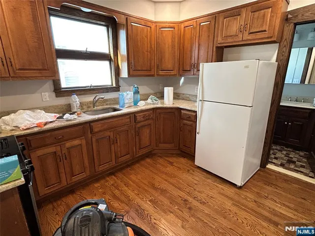 a kitchen with stainless steel appliances granite countertop a refrigerator a sink a stove a refrigerator with wooden cabinets and wooden floor