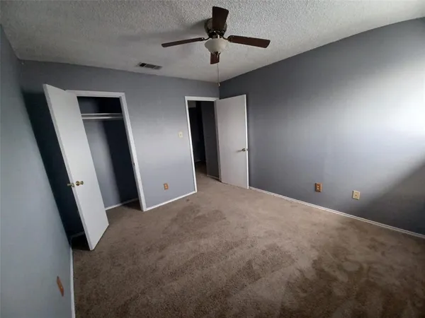 an empty room with closet and chandelier fan