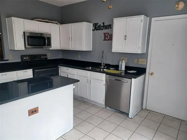 a kitchen with granite countertop white cabinets and black appliances