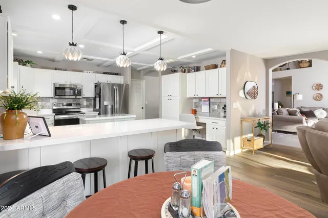 a kitchen with stainless steel appliances kitchen island granite countertop a table chairs and a refrigerator