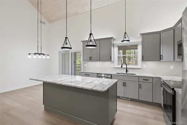 a kitchen with stainless steel appliances granite countertop a sink a stove a refrigerator and island with wooden floor