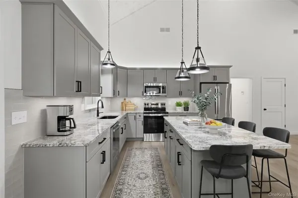 a kitchen with kitchen island granite countertop a sink a counter space appliances and cabinets