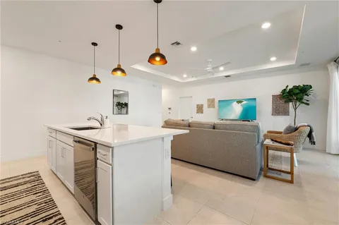 a kitchen with a sink a counter top space and living room view
