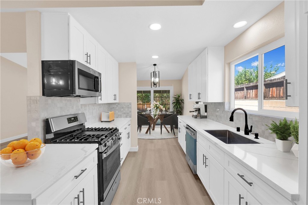 8555 Torbett Way Riverside, CA 92504 - Photo 1 of 1 a kitchen with granite countertop a stove a sink a microwave and cabinets
