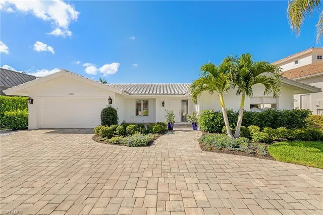 a front view of a house with a yard and potted plants