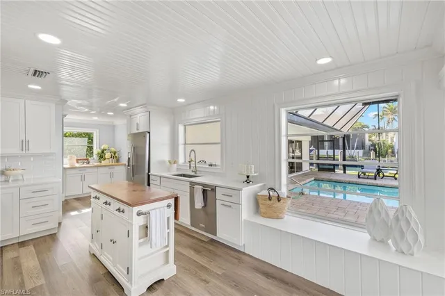 a large white kitchen with cabinets a sink and a stove