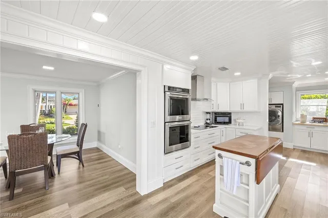 a kitchen with granite countertop kitchen island wooden floors white appliances and cabinets