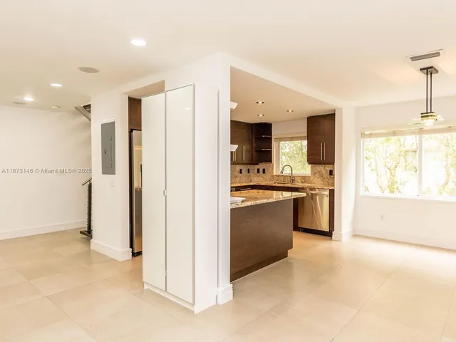 a view of kitchen with stainless steel appliances kitchen island granite countertop a refrigerator and a sink