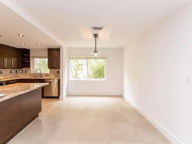 a large kitchen with granite countertop a stove a sink dishwasher and a microwave oven with white cabinets