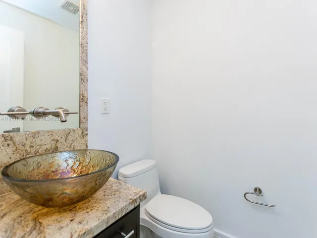 a bathroom with a granite countertop toilet and a sink