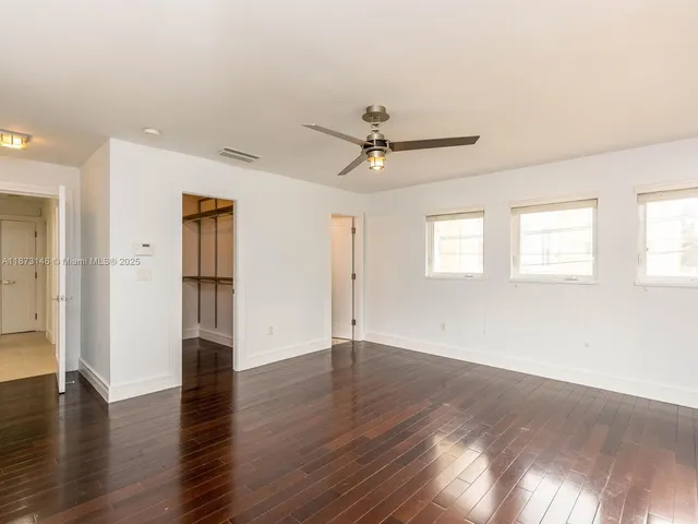 a view of an empty room with a window and wooden floor