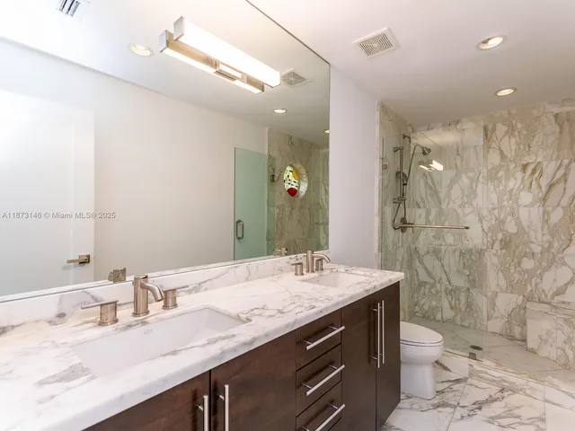 a bathroom with a granite countertop sink toilet a large mirror and shower