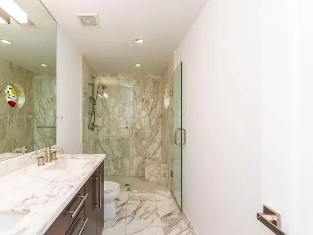 a bathroom with a granite countertop sink a toilet and shower
