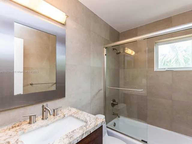 a bathroom with a granite countertop sink toilet and shower