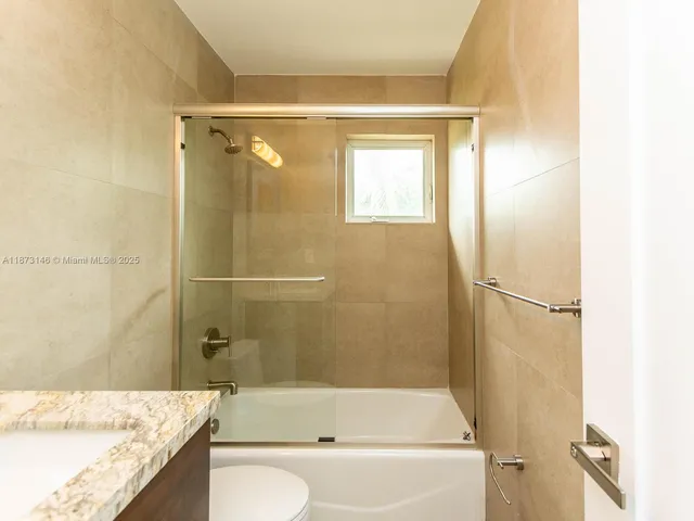 a bathroom with a granite countertop bathtub shower sink and toilet