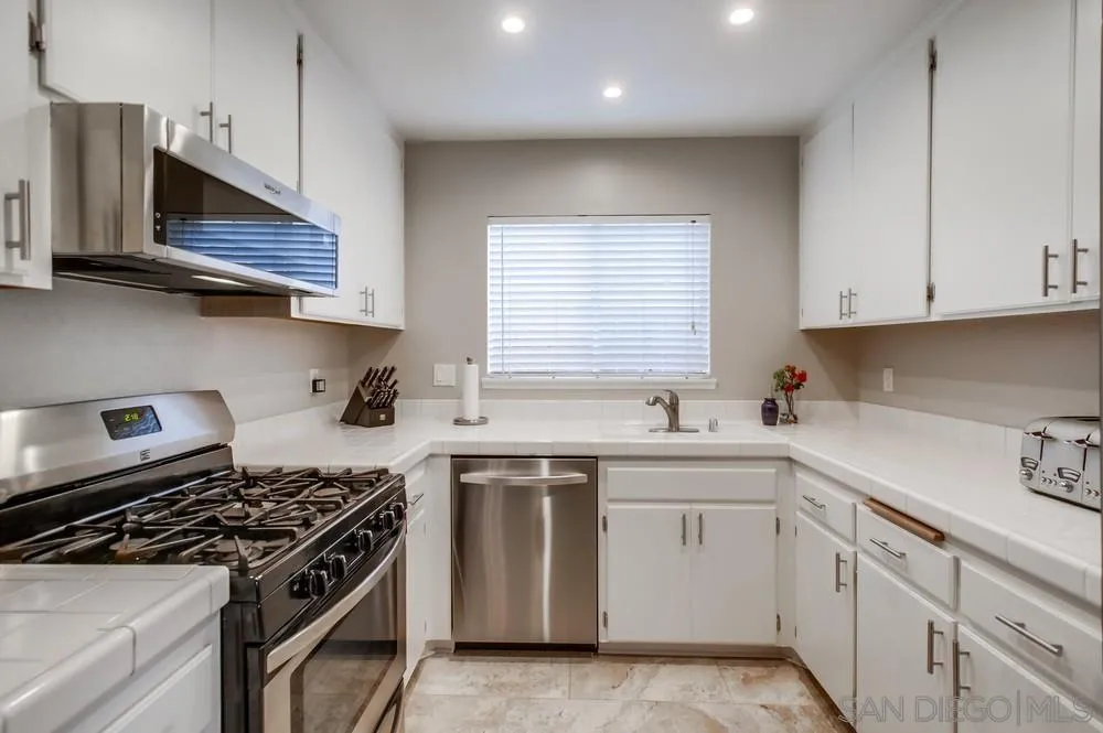 898 Friendly Circle El Cajon, CA 92021 - Photo 14 of 38 a kitchen with white cabinets and appliances