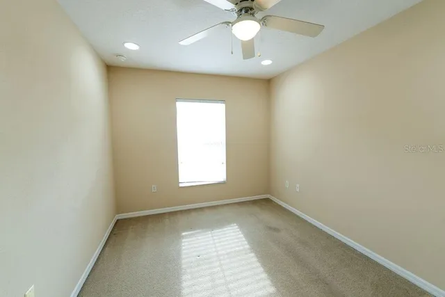 an empty room with a chandelier fan and windows