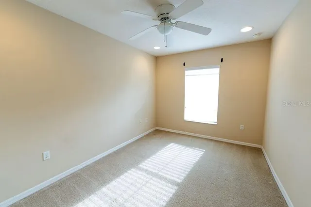 an empty room with a window and a ceiling fan