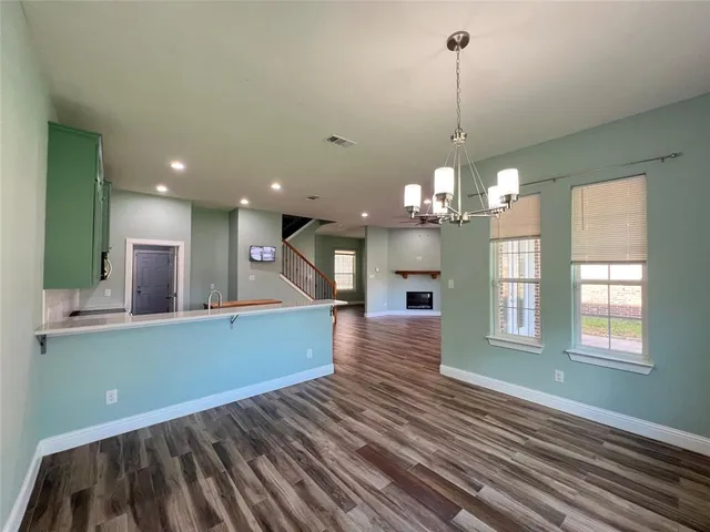 a view of a room with kitchen island stainless steel appliances wooden floor and window